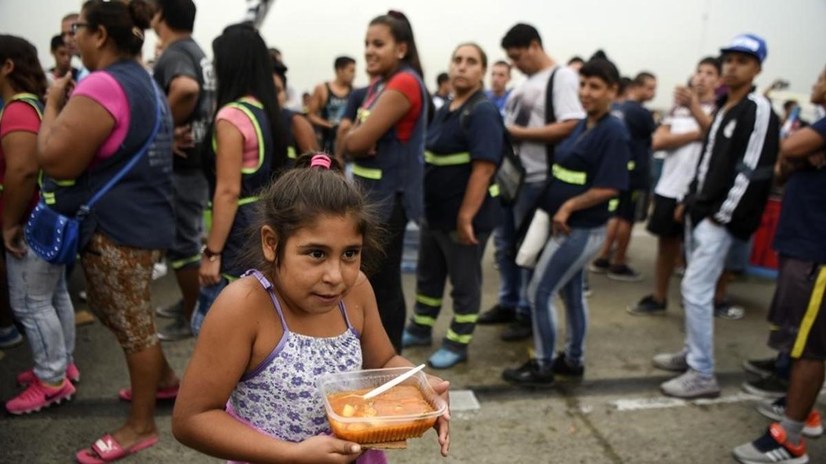 Una niña lleva su ración de comida servida durante una protesta social en Buenos Aires contra la pobreza, el 15 de marzo.