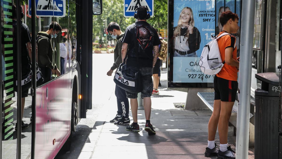 Jóvenes suben a un autobús urbano en una parada del centro.