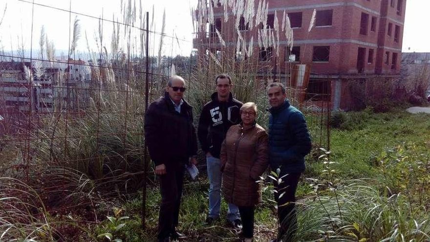 Los vecinos, en la parte trasera de su bloque, en la parcela que debía acoger la zona verde y en la que solo hay un socavón, maleza y un edificio inacabada.