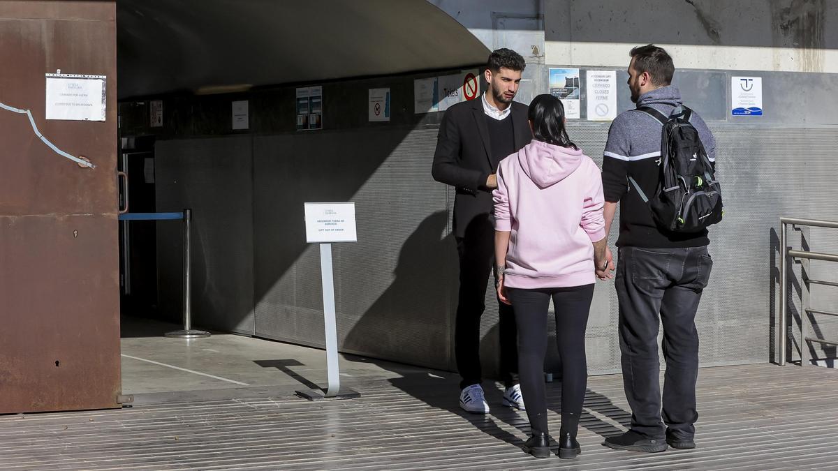 Un informador explica a dos turistas alternativas de acceso, ante el cierre de los ascensores por una avería