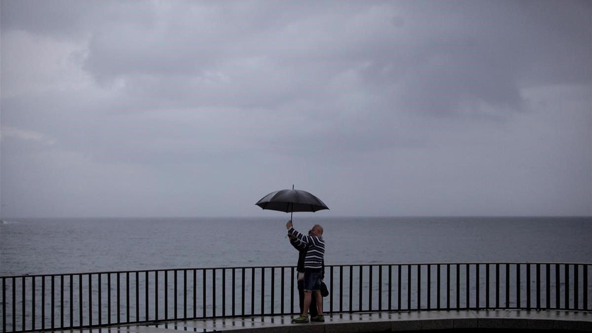 Dos personas se fotografía en el paseo marítimo de A Coruña en medio de una jornada lluviosa, el 12 de agosto del 2020