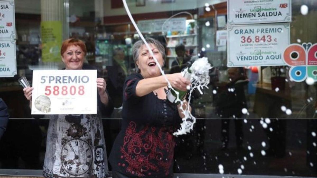 Las loteras María Jesus (d) y Begoña celebran el reparto del quinto premio de la lotería de Navidad, que le ha tocado al número 58808, en un punto de venta de la calle Castaños de Bilbao.