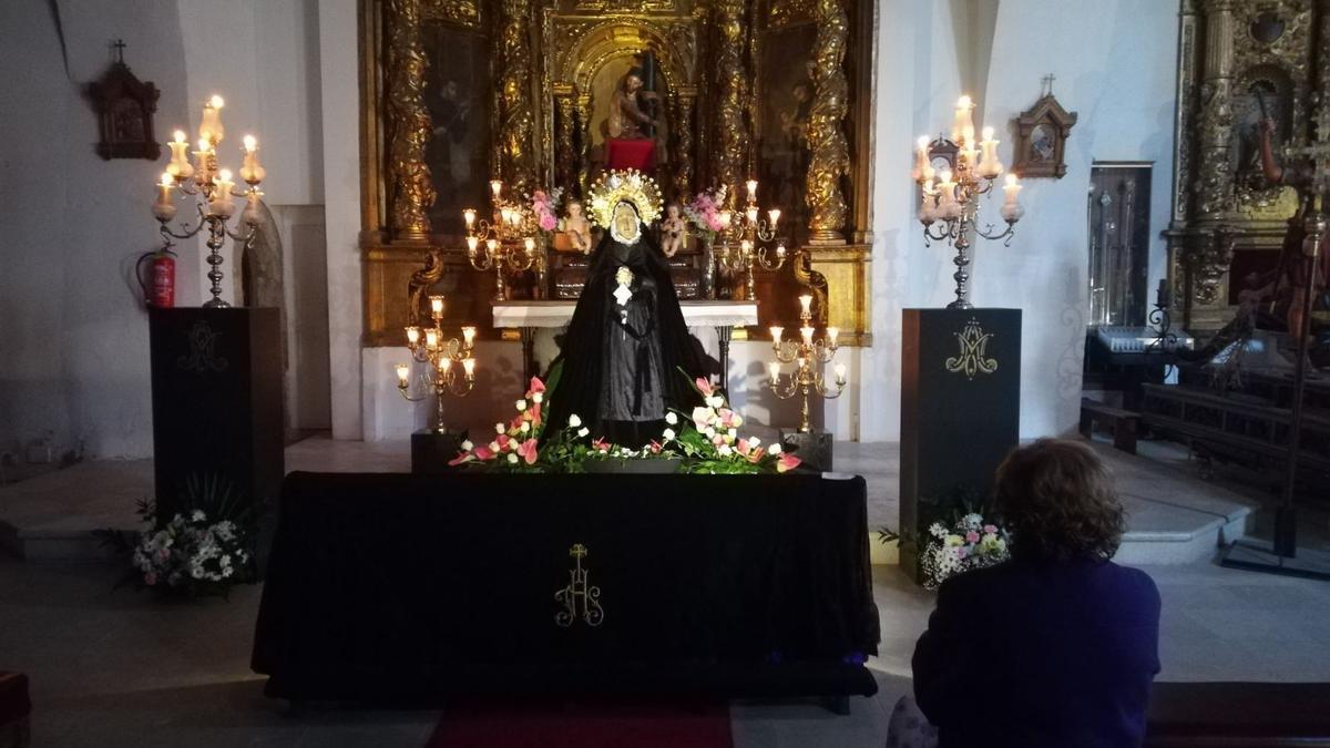 Una mujer observa a la Virgen de la Soledad en la Iglesia de Santa Catalina