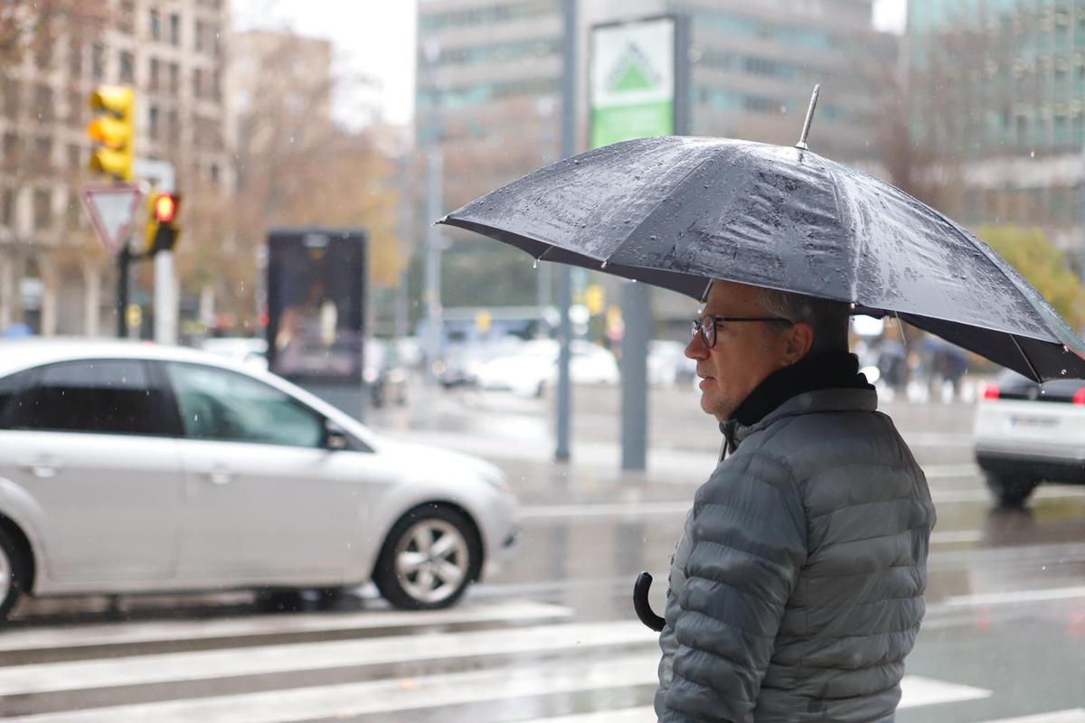 Un hombre se cubre de la lluvia con un paraguas en Zaragoza