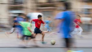 Unos chicos juegan a fútbol en una plaza del Poble Sec.