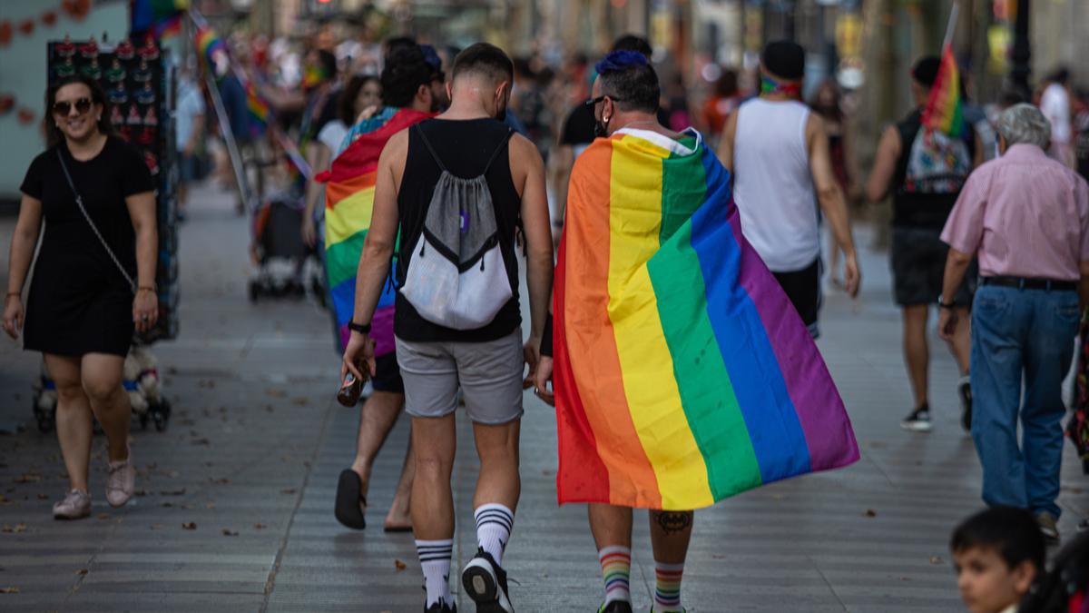 Una pareja camina con una bandera arcoíris.