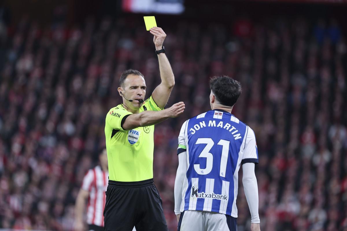 BILBAO, 01/02/2026.- El defensa de la Real Sociedad Jon Martín (d) ve una tarjeta amarilla durante el encuentro correspondiente a la jornada 22 que Athletic Club y Real Sociedad disputan hoy domingo en el estadio de San Mamés, en Bilbao. EFE / Luis Tejido