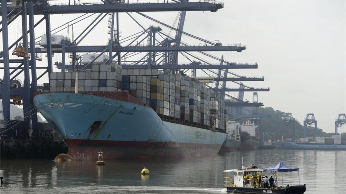 Un barco carga contenedores al lado del nuevo Canal de Panamá.