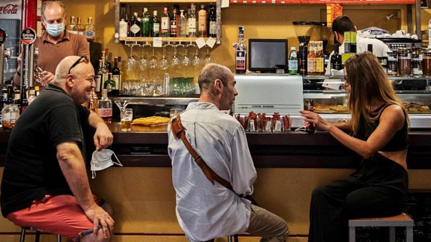 Tres clientes del Bacoro, en la calle Bonaire de València, charlan mientras Luca sirve una cerveza.  | GERMÁN CABALLERO