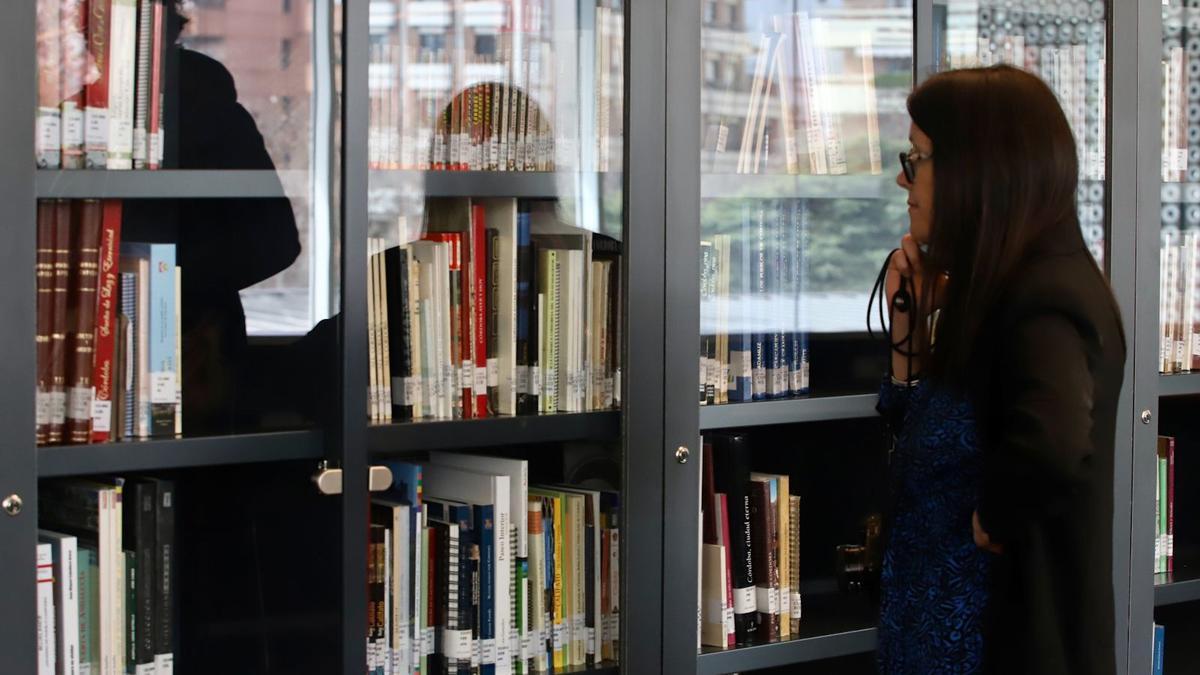 Una mujer observa los estantes de libros de la biblioteca Grupo Cántico, el día de su apertura.