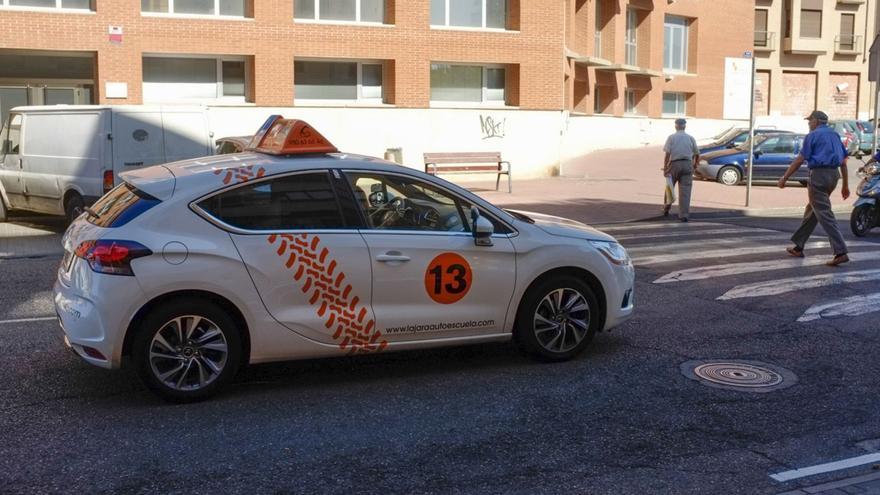 Un coche de autoescuela circula por la avenida de El Ferial junto al edificio del Ayuntamiento.