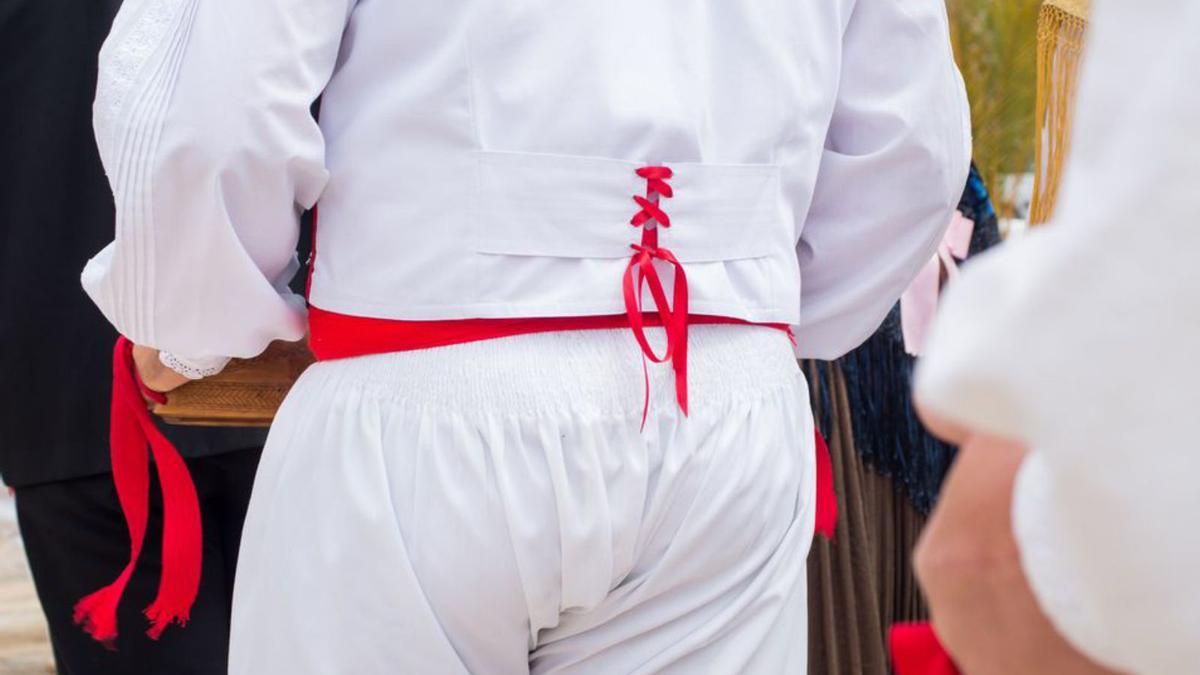 Un jove ballador, d’esquenes, preparat per sortir a ballar amb el vestit i els instruments tradicionals. 