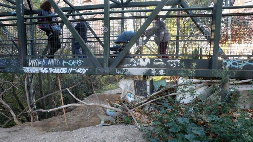 Acumulación de ramas, basura y cartones debajo de la pasarela peatonal sobre el río. | ANDREEA VORNICU