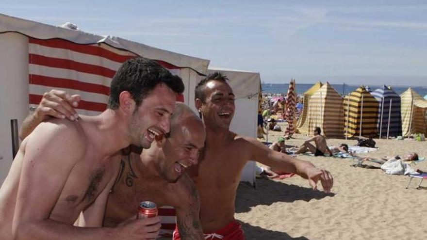 Cuatro jóvenes, ayer, en la playa de San Lorenzo.