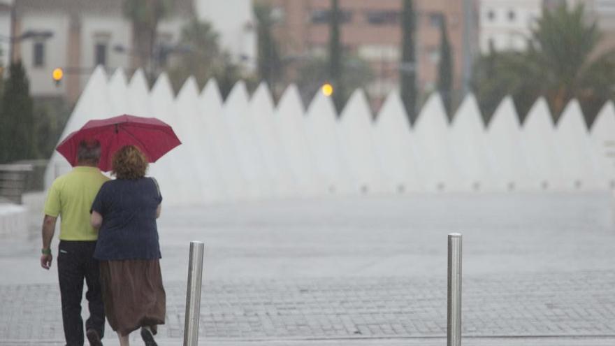 Una pareja se protege de la lluvia bajo un paraguas.