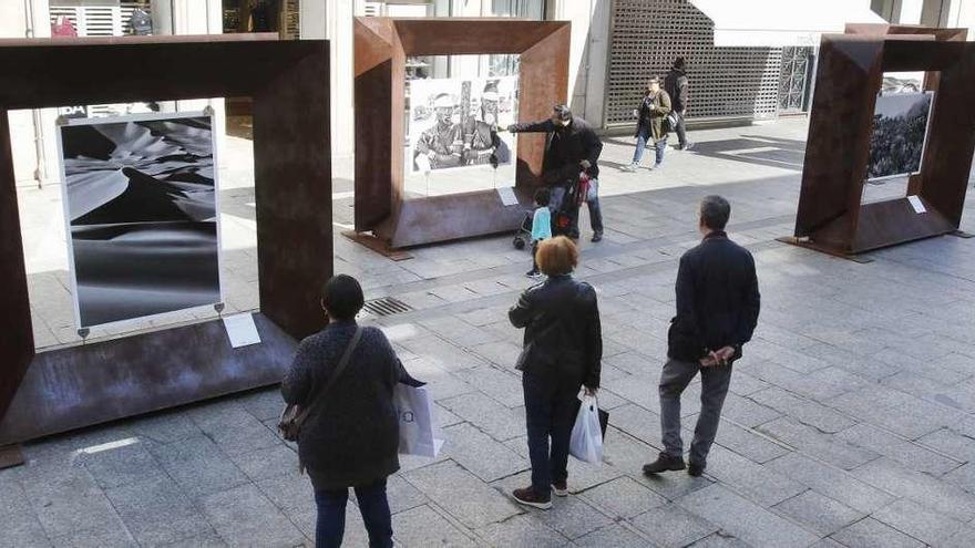 Transeúntes detenidos ante las fotografías de la muestra. // A. Villar