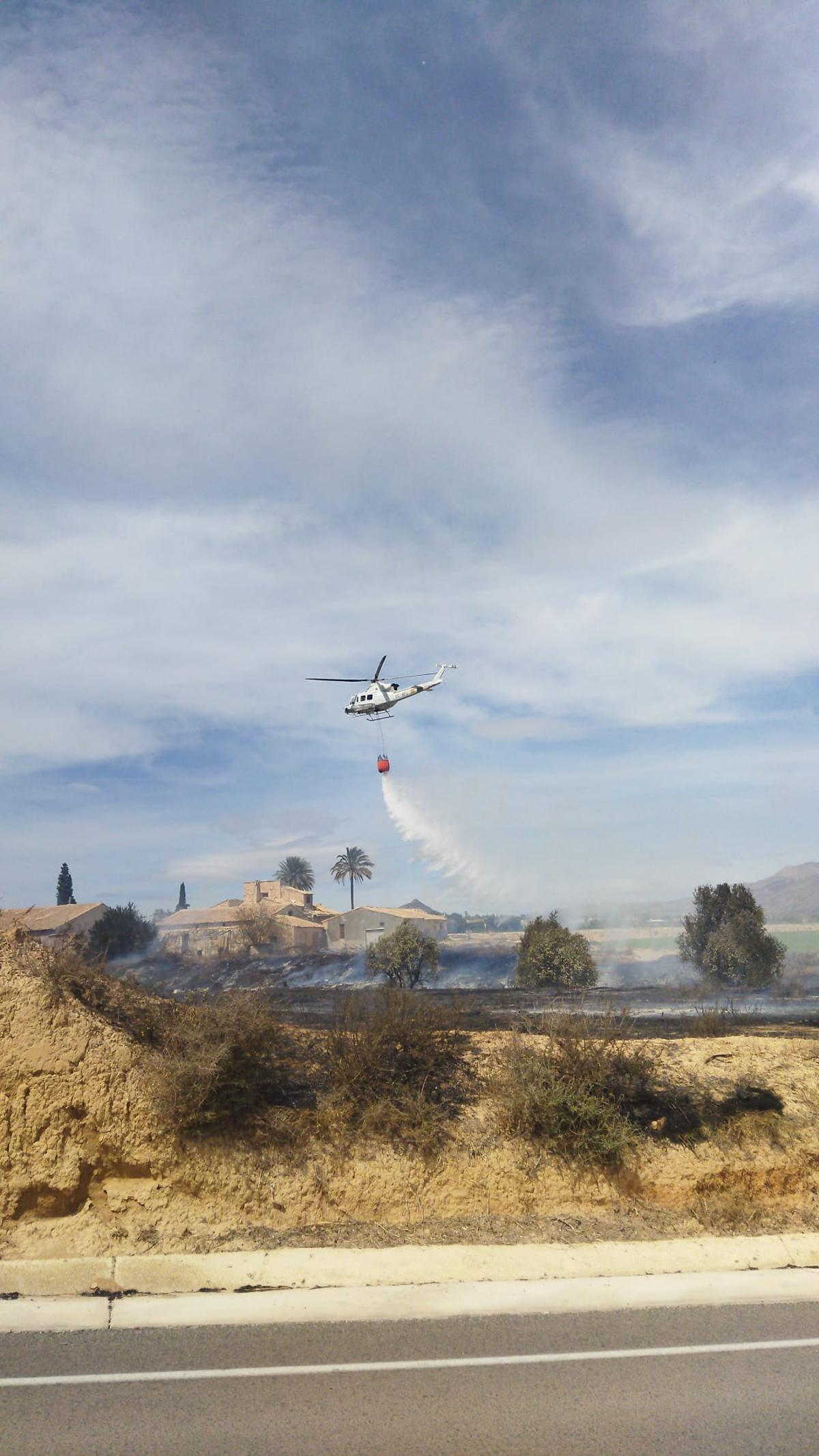 Un helicóptero tratando de evitar que las llamas alcancen un caserío.