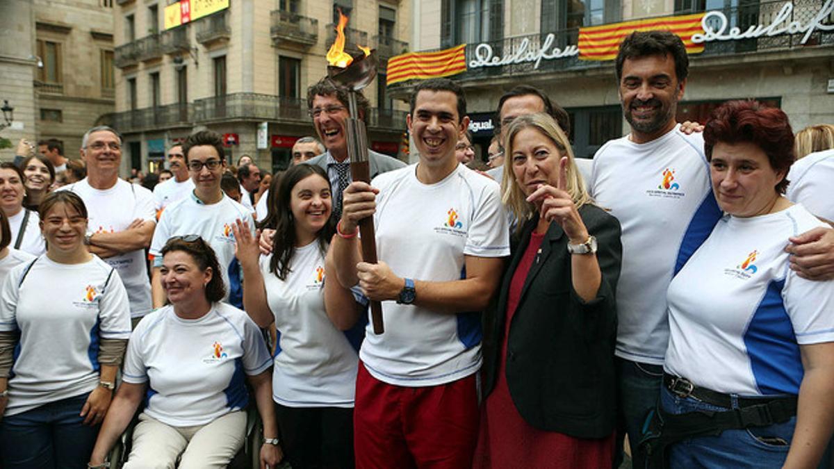 El extenista Sergi Bruguera (derecha), el atleta Kilian Vera y la 'consellera' de Benestar Social, Neus Munté, posan con la antorcha de los Special Olympics, en al plaza de Sant Jaume