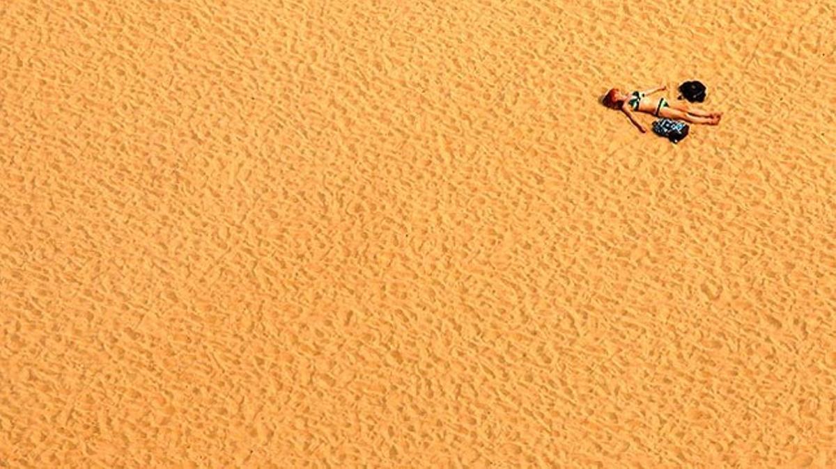 Una dona pren el sol sobre la sorra d’una platja a Pusan (Corea del Sud). Les relacions diplomàtiques entre Corea del nord i Corea del Sud es troben en el seu punt més tens en anys.