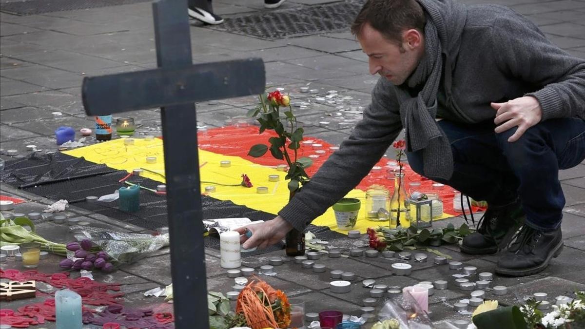 Un hombre deja flores en el tributo a las víctimas de los atentados de Bruselas.
