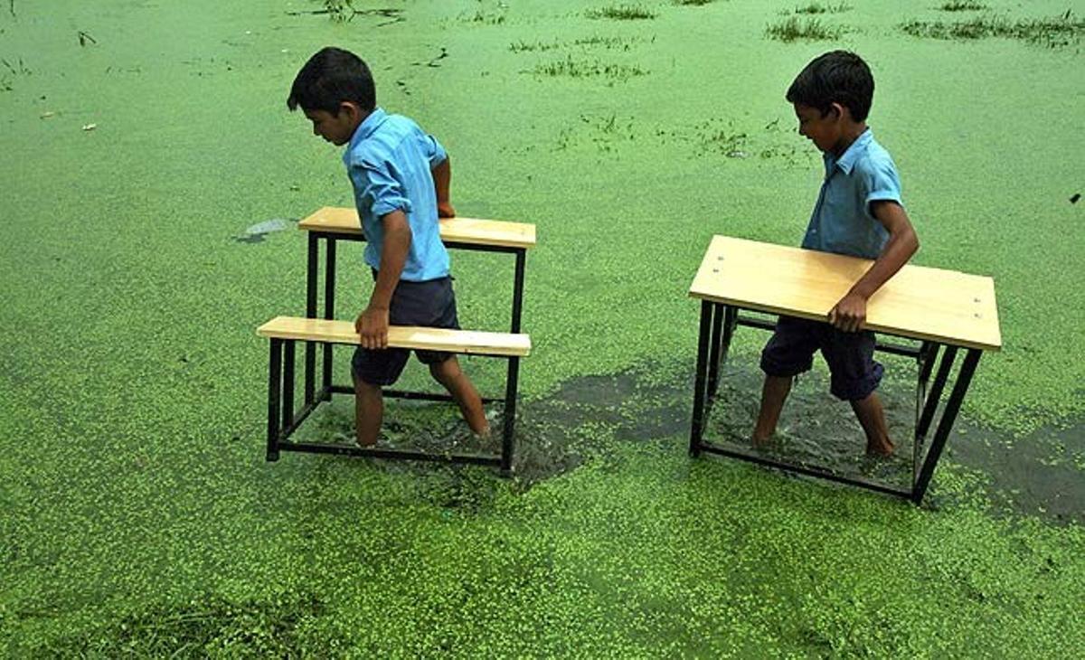 Dos nens traslladen els seus pupitres després de la inundació de la seva escola al poble de Bassi Kalan, als voltants de Jammu (Índia).