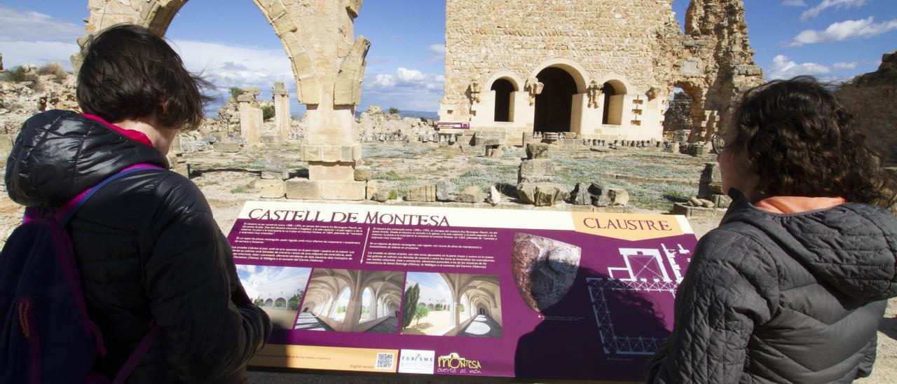 Dos visitantes ante un panel explicativo de los elementos exteriores del castillo.