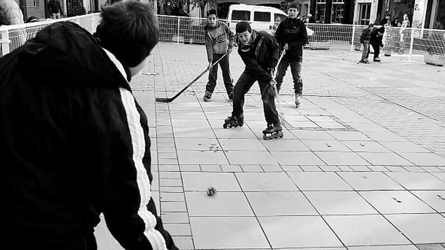 Un grupo de chavales juega al hockey en la Plaza de la Madera y un padre enseña a su hija a patinar ayer al mediodía.