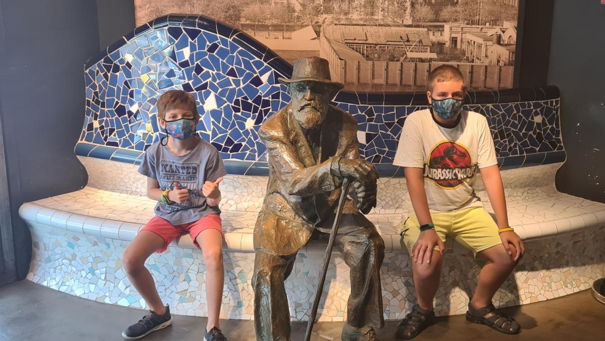 Dos niños posan junto a la escultura de Antoni Gaudí.