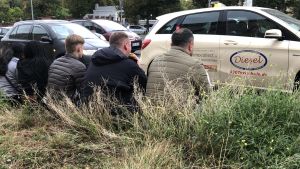 Tres hombres comen un döner sentados en un bordillo.