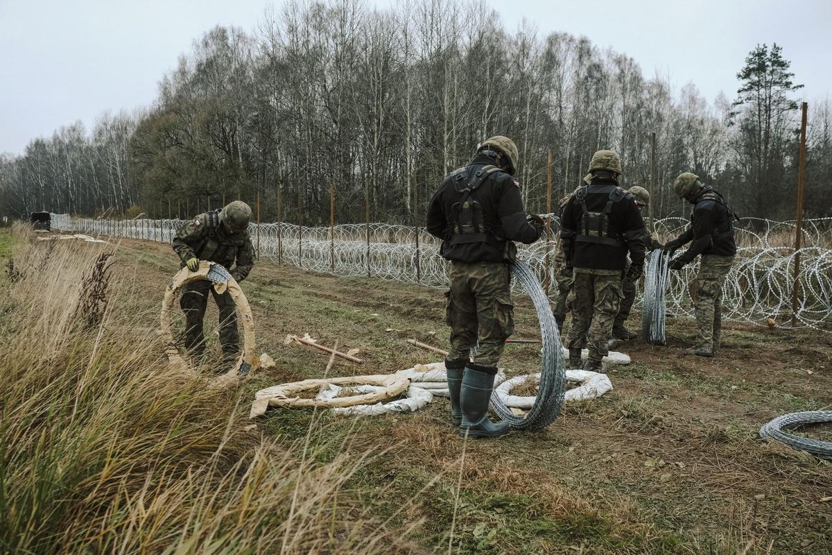 Soldados del ejército polaco arreglan bobinas de alambre de púas en una valla a lo largo de la frontera polaca, con el enclave ruso de Kaliningrado, cerca de Zerdziny, Polonia