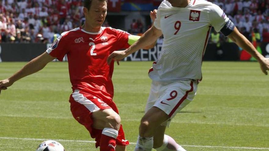 Stephan Lichsteiner y Robert Lewansdowski disputan un balon en el partido de octavos de la Eurocopa.