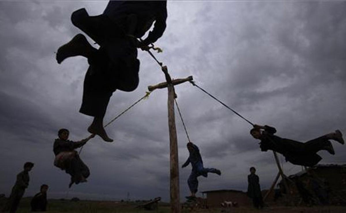 Diversos nens refugiats afganesos juguen en un gronxador casolà als afores d’Islamabad (Pakistan).