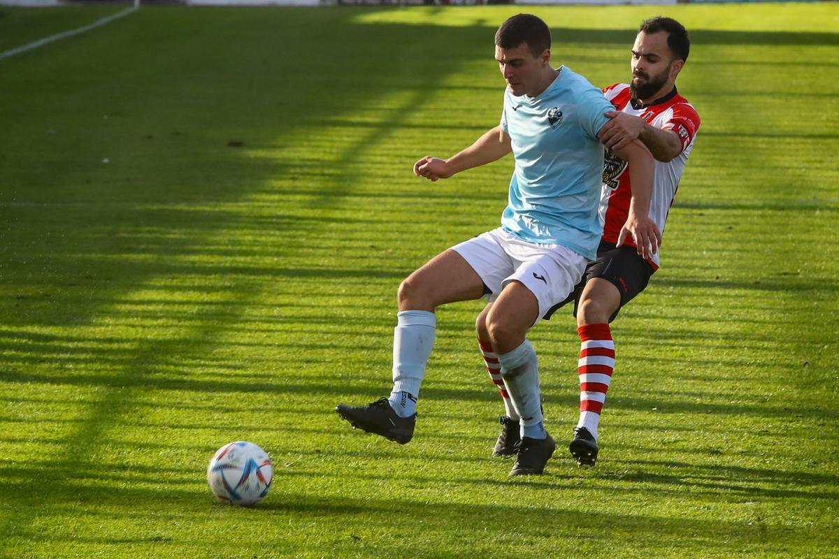 Un futbolista del Beluso protege el balón ante la presión de uno del Céltiga.