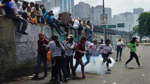 Manifestantes corren entre el gas lacrimógeno lanzado por la policía, durante la marcha contra Maduro, en Caracas, el 19 de abril.