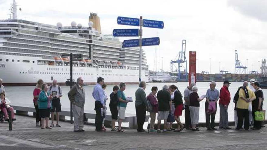 Pasajeros en el muelle, esperando la guagua turística.