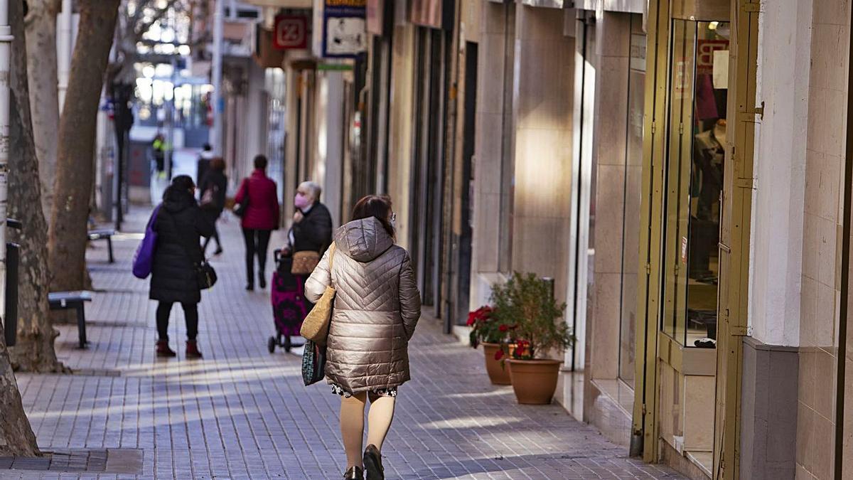 Una vecina de Xàtiva observa el escaparate de una tienda de la ciudad, en una imagen de ayer | PERALES IBORRA