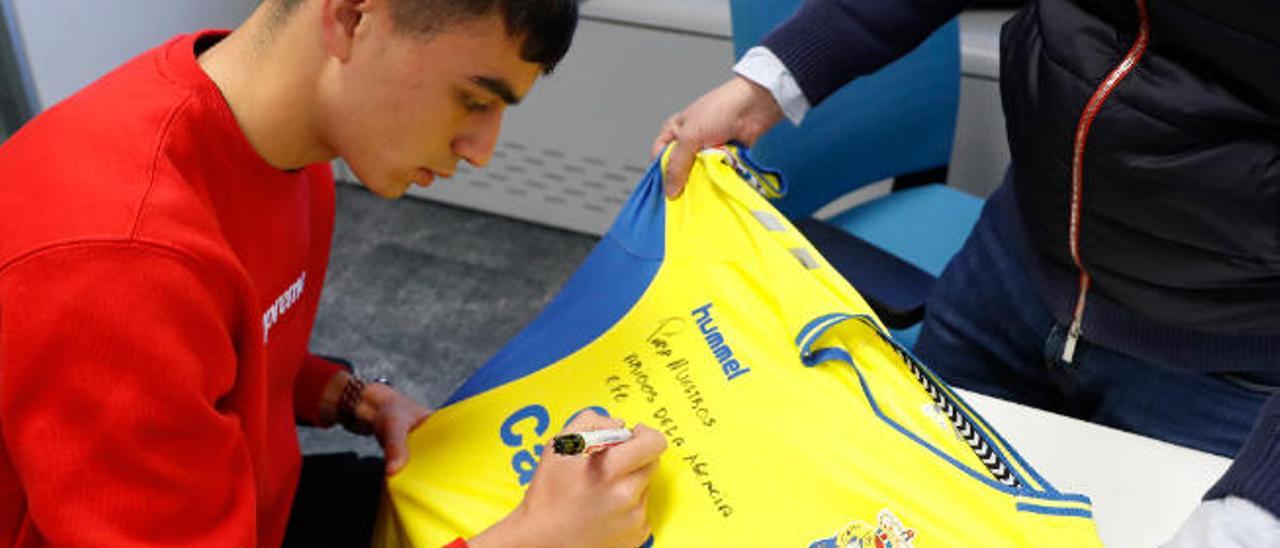 Pedri González, futbolista de la UD Las Palmas, firma una camiseta amarilla en la sede central de la Agencia Efe, en la Avenida de Burgos en Madrid.