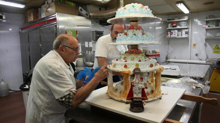 Zenón Pascual y Julio Pascual, dos generaciones juntas elaborando en el obrador la gran tortada de ocho pisos.