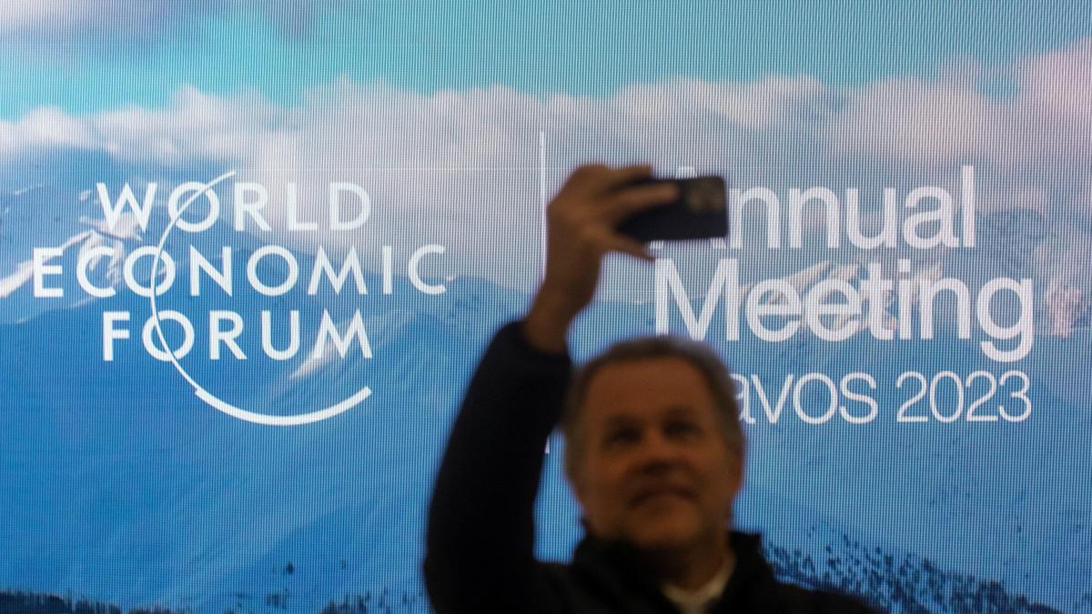 Un home es fa una selfie davant el cartell del Fòrum Econòmic de Davos