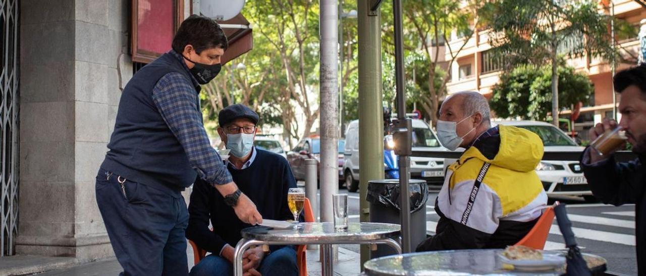 Un camarero de una terraza de Santa Cruz le sirve una caña a un cliente.