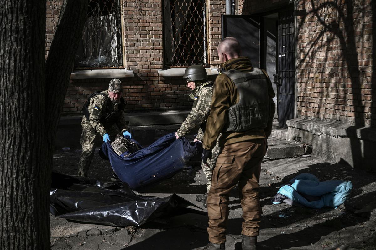 Los miembros del servicio militar de emergencia retiran el cuerpo de un militar ucraniano muerto en el área del instituto de investigación de la Academia Nacional de Ciencias de Ucrania, después de un ataque, en el noroeste de Kiev.