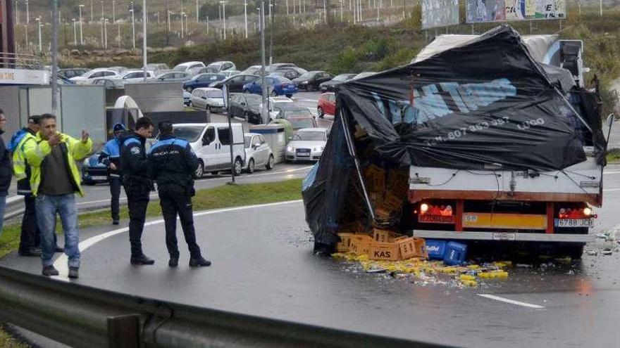 El camión accidentado, con las cajas de bebida y las botellas que transportaba en el asfalto.