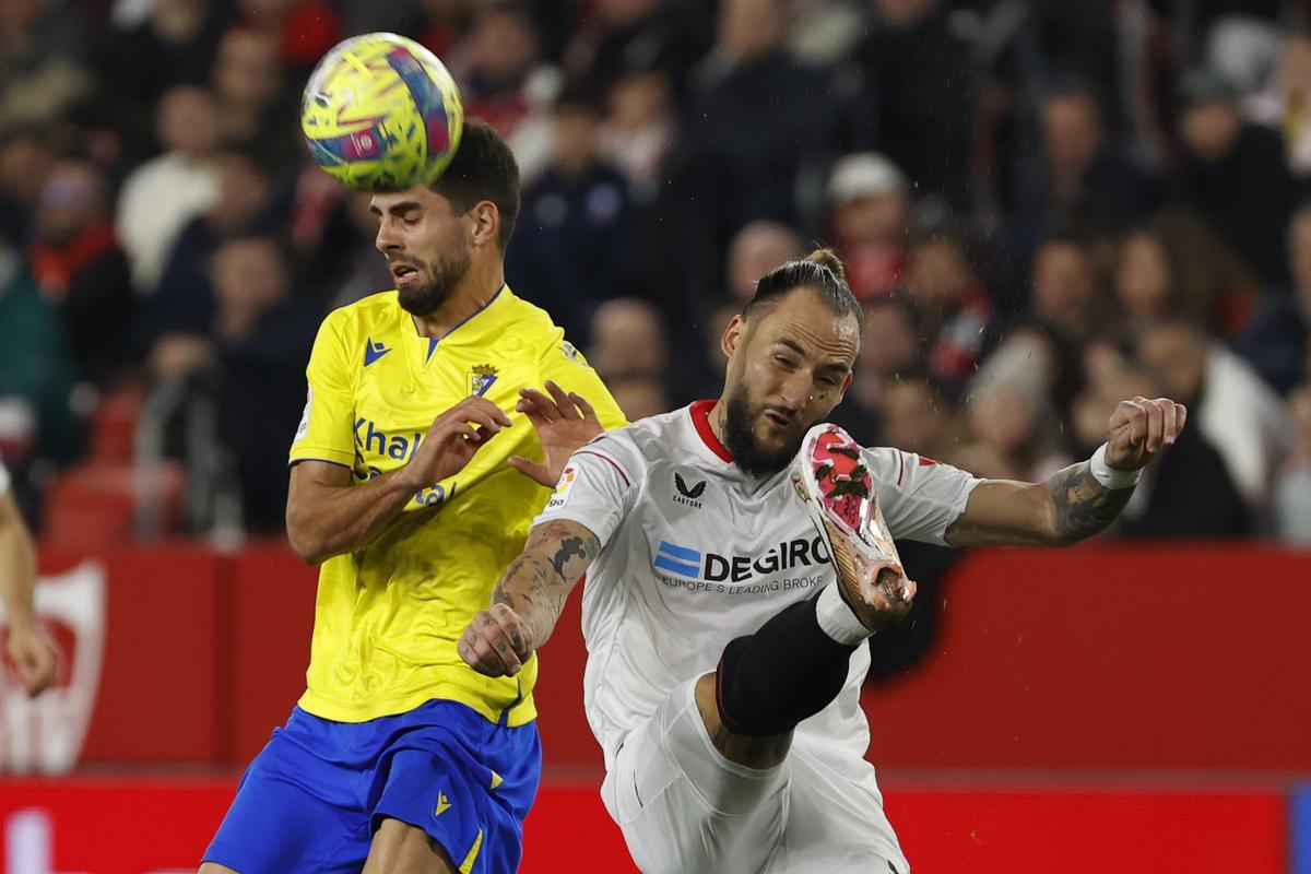 SEVILLA, 21/01/2023,- El centrocampista serbio del Sevilla Nemanja Gudelj (d) pelea un balón con el delantero Rubén Sobrino, del Cádiz, durante el partido de la jornada 18 de LaLiga que estos dos equipos juegan hoy sábado en el estadio Sánchez Pizjuán. EFE/ Julio Muñoz