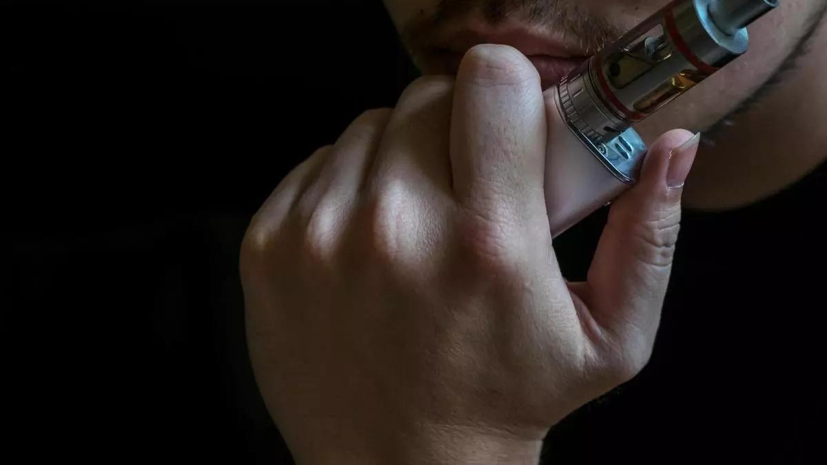 Un joven fumando un cigarrillo electrónico.