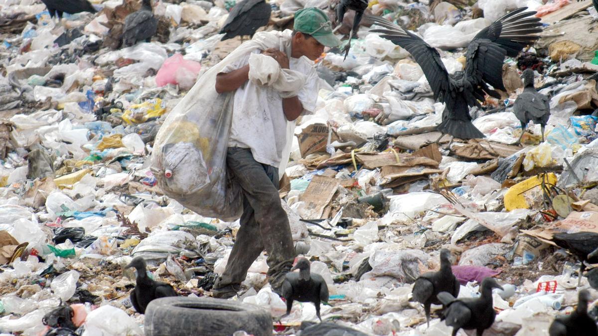 Un recogedor de basura busca materiales reciclables en un vertedero municipal del este de Tegucigalpa (Honduras), con la esperanza de poder revenderlos y obtener algún dinero con el que alimentar a sus familias.