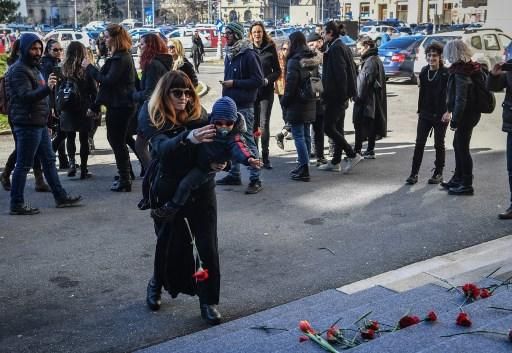 Una mujer con un niño deposita un ramo de flores en la sede del Ministerio del Interior de Rumanía en protesta por la violencia machista en una manifestación por el Día de la Mujer.