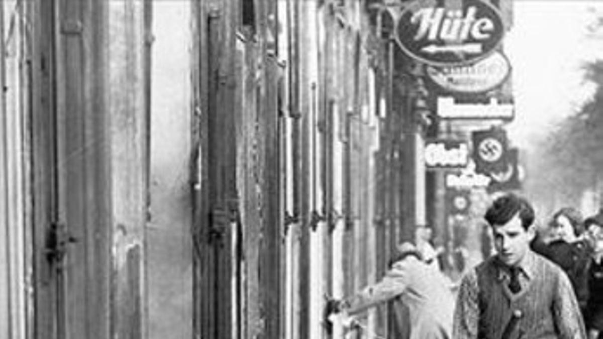 Un joven limpia los cristales de una tienda judía, en 1938.