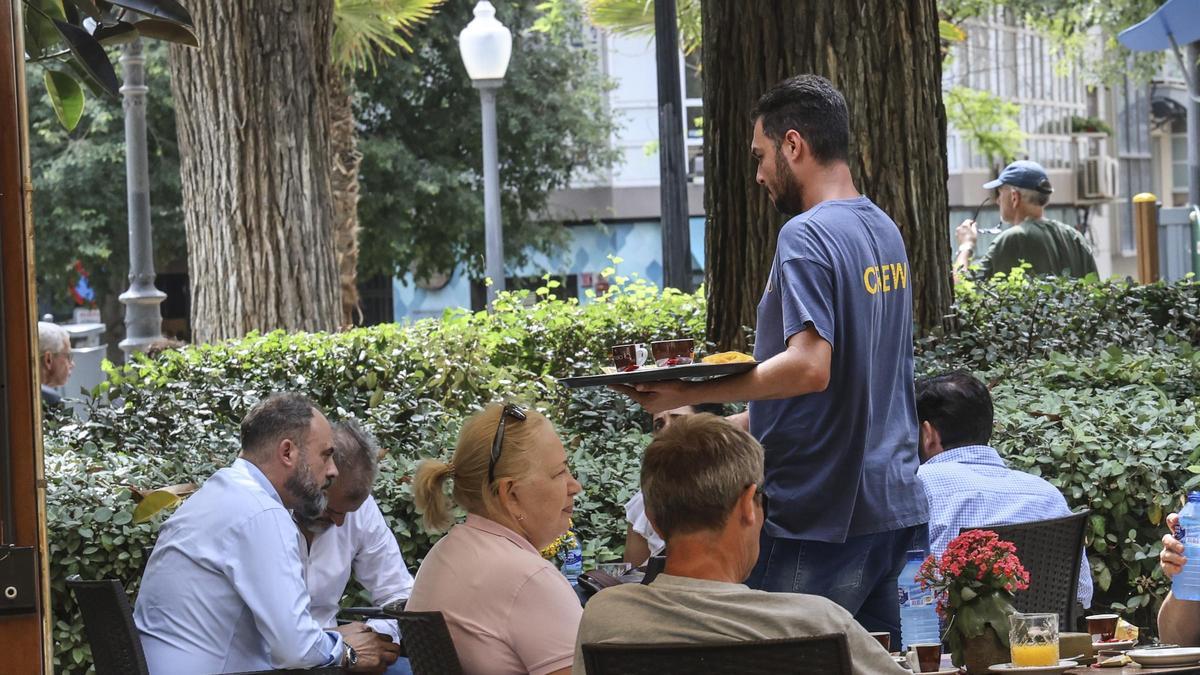 Un camarero atiende a los clientes de una terraza en la ciudad de Alicante.