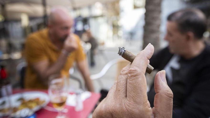 Una persona sujeta un purito junto a una mesa de una terraza de hostelería. |  // FERRAN NADEU