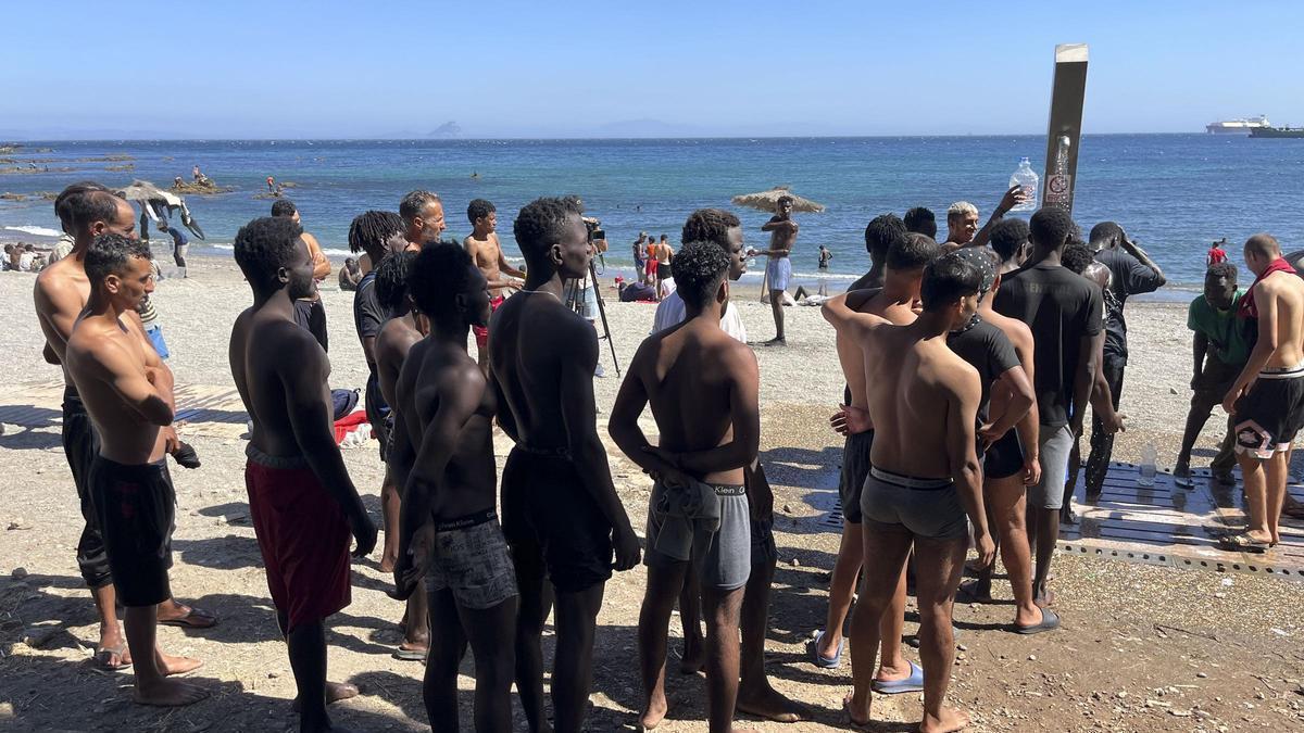 Migrantes se duchan en la playa de Ceuta, alguno de ellos menores.